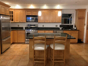 BEFORE Lynnfield Contemporary Kitchen with brown cabinetry and black countertops.