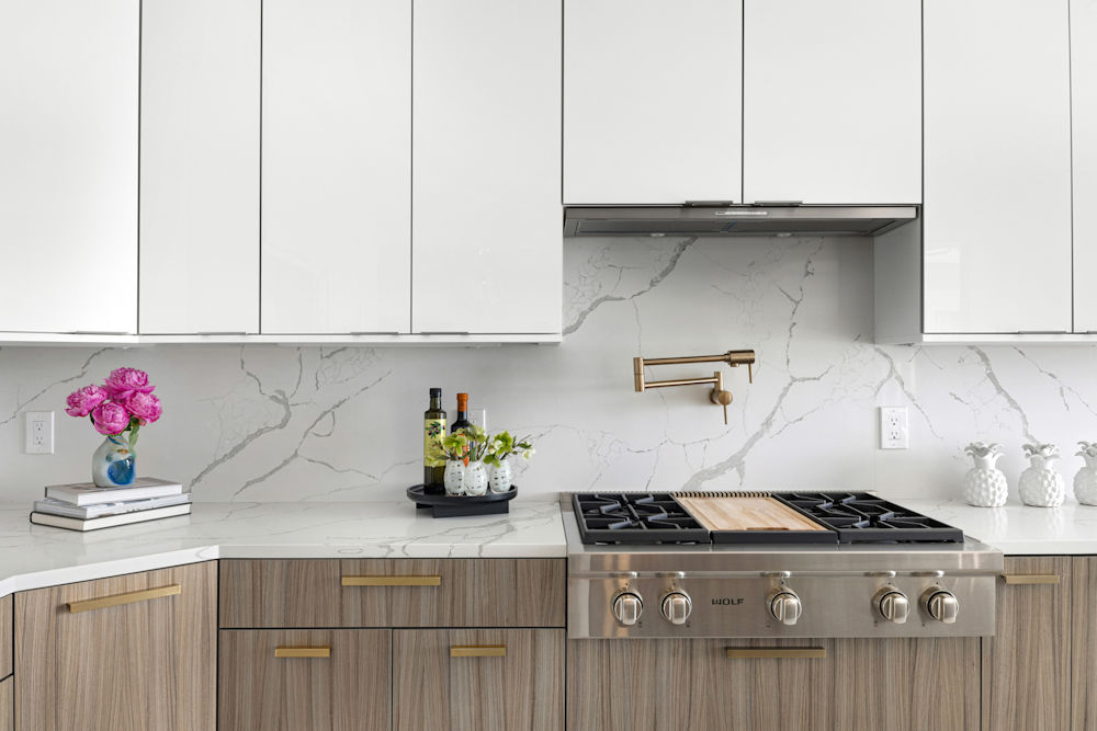 Contemporary kitchen closeup of Wolf range top, and full height quartz backsplash with pot filler.