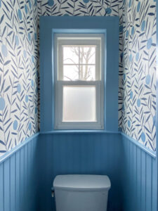 Powder room remodel with bold mod wallpaper and beadboard halfway up the walls painted in cornflower blue