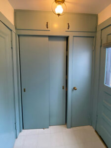 Before photo of mudroom with sliding closet doors painted light blue