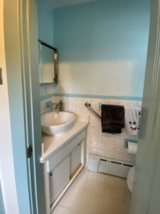 Before photo of a powder room with tiles halfway up the wall and built in vanity
