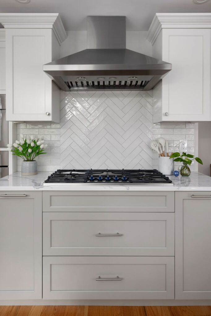 Kitchen remodel in Andover with white and gray cabinets, quartz countertops, and white tile backsplash in a herringbone pattern.