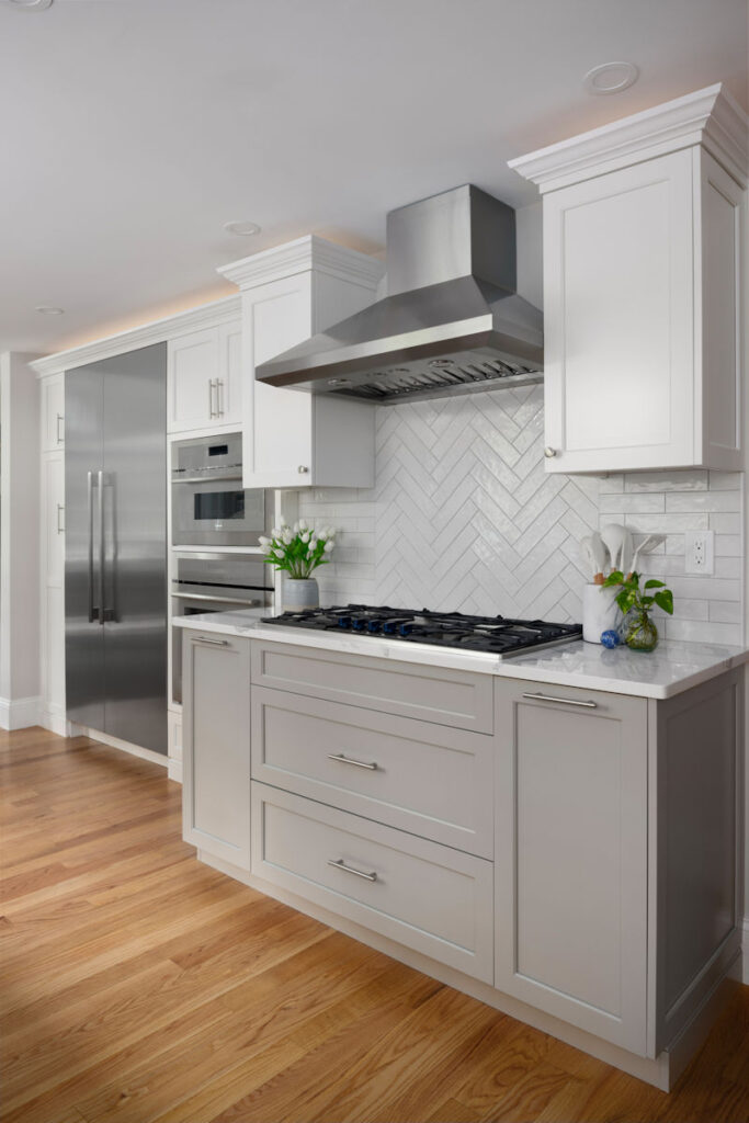 Kitchen remodel in Andover with white and gray cabinets, quartz countertops, and white tile backsplash in a herringbone pattern