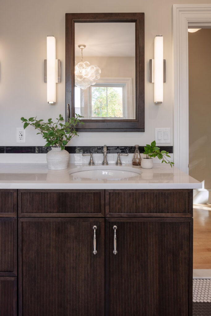 Bathroom remodel with dark stained reeded vanity cabinetry with quartz countertop - McGuire + Co. Kitchen & Bath