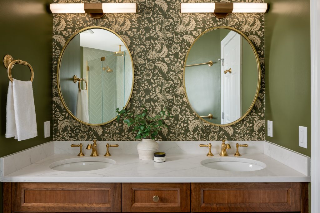 Winchester Bathroom Remodel with cherry double-sink vanity, gold fixtures and hardware, basketweave tile floor, and Mind the Gap Tyrol Garten Juniper wallpaper wall covering